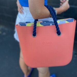 OBAG Tote: coral tote, dark blue handles and multicolor lining.